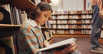 Woman, reading book and floor in library for literature, research and studying for knowledge. Person, student and novel with academic information, scholarship and learning for education assignment