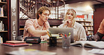 Students, man and women with laptop at library for group project, research and education at university. People, computer and together with books, assessment and learning for scholarship at college