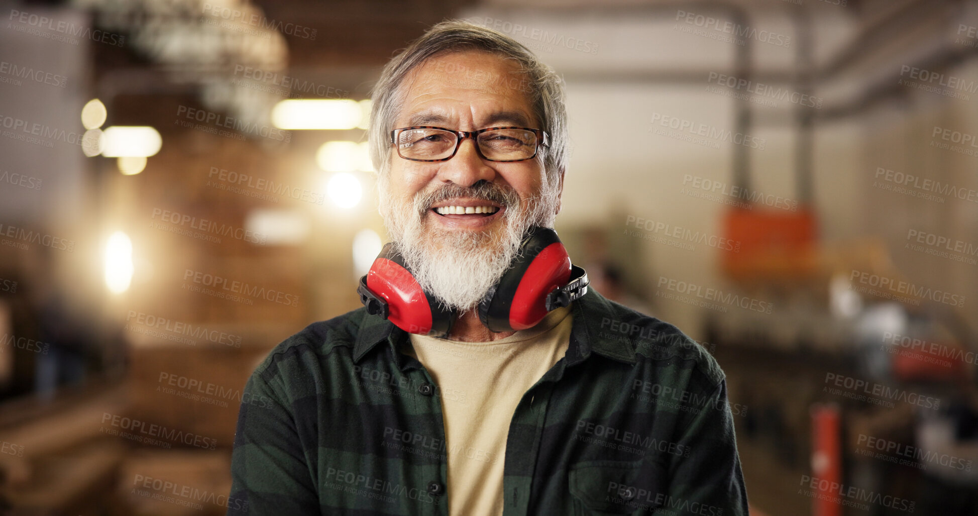 Buy stock photo Portrait, happy carpenter and mature man in workshop for furniture manufacturing and production. Woodwork, smile and Asian person at industrial factory for joinery with headphones for ear protection