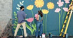 Back, creative and couple painting on wall for art project, mural design and renovation of community. Happy, people and artist hobby for improvement, diy decoration and makeover for flowers aesthetic