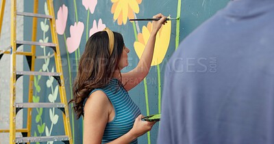 Buy stock photo Woman, creative and painting in city for wall art, mural process or project to uplift community. People, team creativity or outdoor with paintbrush for floral design, volunteer collaboration or hobby