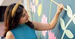 Woman, smile and painting in city for mural art, creative wall and social responsibility to uplift community. Volunteer, creativity and outdoor with project for floral design, public service and DIY