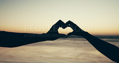 Buy stock photo Couple, heart hand and silhouette on beach for love, romantic date and bonding together. People, sign and affection of tropical vacation, partner loyalty and trust of relationship commitment at ocean