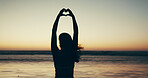 Sunset, beach and woman with heart hands for travel, vacation or getaway with calm in evening. Ocean, silhouette and back of female person on seaside weekend trip with love hand gesture or emoji.