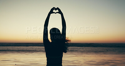 Buy stock photo Sunset, beach and woman with heart hands for travel, vacation or getaway with calm in evening. Ocean, silhouette and back of female person on seaside weekend trip with love hand gesture or emoji.