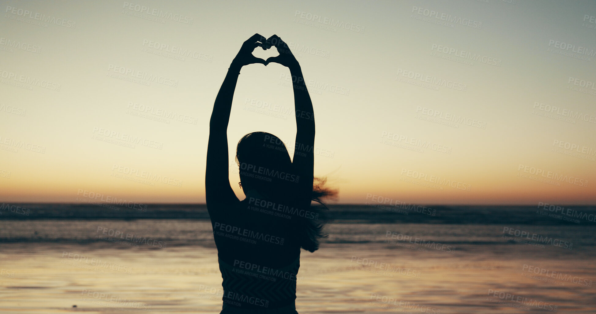 Buy stock photo Sunset, beach and woman with heart hands for travel, vacation or getaway with calm in evening. Ocean, silhouette and back of female person on seaside weekend trip with love hand gesture or emoji.