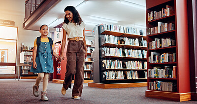 Buy stock photo Education, woman and child in library, bookshelf and holding hands with student, walking and backpack. Knowledge, growth and development of kid with books, learning and teacher with girl in school