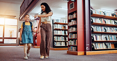 Buy stock photo Education, woman and child in library, smile and holding hands with student, walking and backpack. Knowledge, growth and development of kid with books, learning and teacher with girl in school