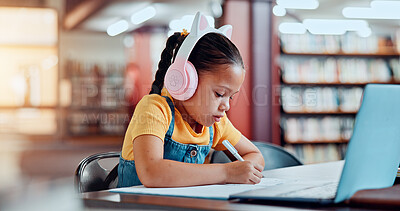 Buy stock photo Child, writing and laptop with headphones in library for elearning class, online teaching platform or assessment. Distance learning, education or girl student with books for study lesson or knowledge