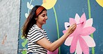 Painting, mural and woman in city with flowers for art design, creative project and community service. Artist, happy and person with paintbrush outdoor for wall decor, inspiration and DIY hobby