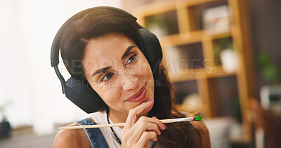 Buy stock photo Thinking, woman and painter with headphones at house for streaming music, podcast audio and art ideas. Smile, person and thoughts with paint brush for planning, decision and process for creativity 