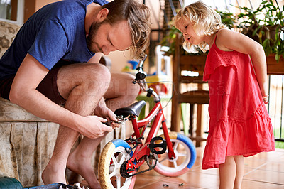 Buy stock photo Bicycle, repair and man in home with kid for help, teaching and learning together for bonding with daughter. Maintenance, support and dad fixing bike for girl with tools, care and child development