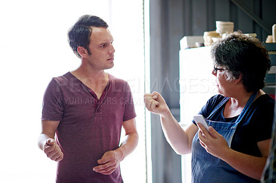 Buy stock photo Small business, artisan and colleagues with ideas, discussion and planning for promotion with smartphone. Entrepreneur, man and talking to woman for project, mobile and creativity for collaboration