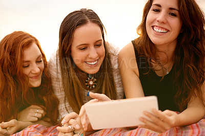 Buy stock photo Happy women, tablet and relax with friends for social media, communication or outdoor picnic. Female people, smile and lying on blanket with digital technology for holiday, vacation or post in nature