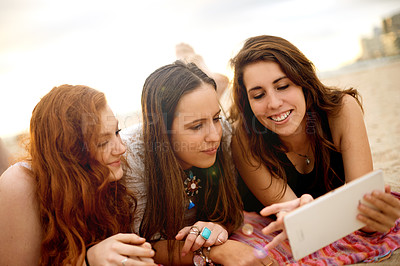 Buy stock photo Tablet, relax and girl friends on beach for social media, online or app on vacation, getaway or weekend trip. Happy, digital technology and group of female people reading blog on tropical holiday.