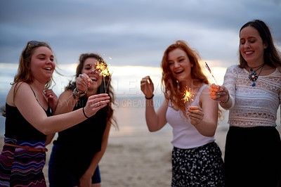 Buy stock photo Beach, happy and girl friends with sparklers for celebration, party or social gathering at event. Smile, fun and group of people with firework stick by ocean for spring break, holiday or vacation.