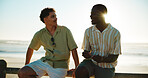 Men, talking and friends at beach for break with bonding, communication and support outdoor. Conversation, people and happy on wood fence, travel or vacation to relax with connection in nature