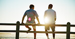 Men, sunset and back of friends at beach for break with bonding, thinking and support outdoor. Conversation, people and flare by wood fence, travel or vacation to relax with connection in nature
