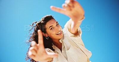 Buy stock photo Finger frame, blue sky and portrait of woman for social media post, profile picture or blog. Tongue out, smile and face of female person from Colombia with photography gesture outdoor from below.