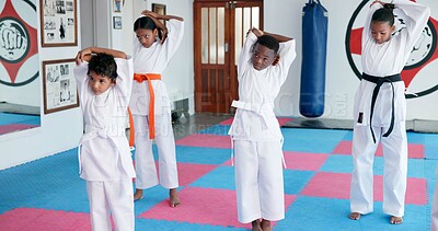 Buy stock photo Children, exercise and stretching for karate class preparation, start lesson or warm up for martial arts. Girls, boys and students in dojo ready for self defense training, taekwondo and sports