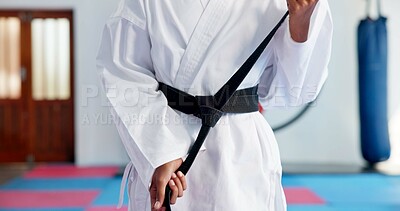Buy stock photo Hands, black belt and person in karate dojo for self defense training, skill level or martial arts. Ready, student and prepare for fight, tying knot for experience and taekwondo with growth or sports