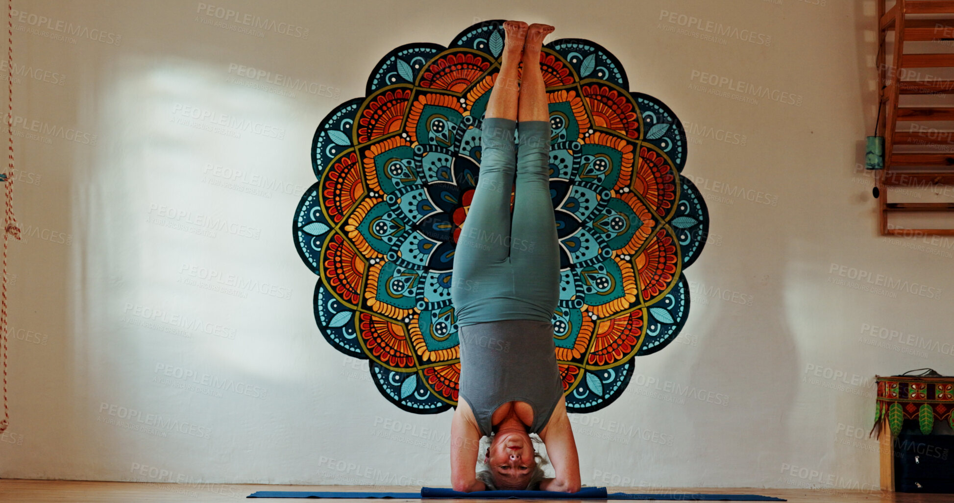 Buy stock photo Balance, upside down or yoga and woman in studio with wall art for fitness or wellness routine. Exercise, headstand or pilates and senior person in class with mandala symbol for holistic health