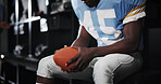 Hands, football and player with ball in locker room for preparation, sports match and waiting on game. Male athlete, getting ready and half time of competition, fitness challenge and tournament event