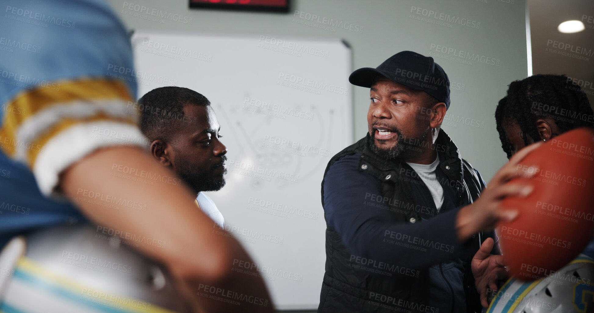 Buy stock photo Talking, man and football with coach and team in locker room for game plan, sports strategy or defense formation. Touchdown tactics, half time feedback and discussion with people and match advice