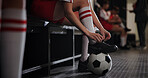 Soccer, foot and tying shoes with ball in locker room for sport preparation, competition or tournament. Person, legs or professional football player getting ready with tie sneakers for game or match