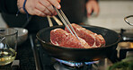 Cooking, stove and hands of chef with meat in pan in kitchen for culinary skill, recipe and meal prep. Food, dinner and person with beef, steak and sauce for gourmet dish, ingredients and cuisine