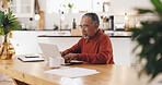 Senior man, laptop and taxes in kitchen with typing, documents and financial review for pension. Elderly person, computer and paperwork with budget, will and planning for retirement income in home
