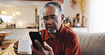 Senior man, phone and confused with living room, sofa and reading online news blog post. Question, digital technology and mature person with internet spam, social media and retirement at home