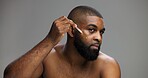Beauty, skincare and serum with black man in studio for facial, grooming and dermatology. Cosmetics, glow and self care with person and oil dropper on gray background for hydration, hygiene or shine
