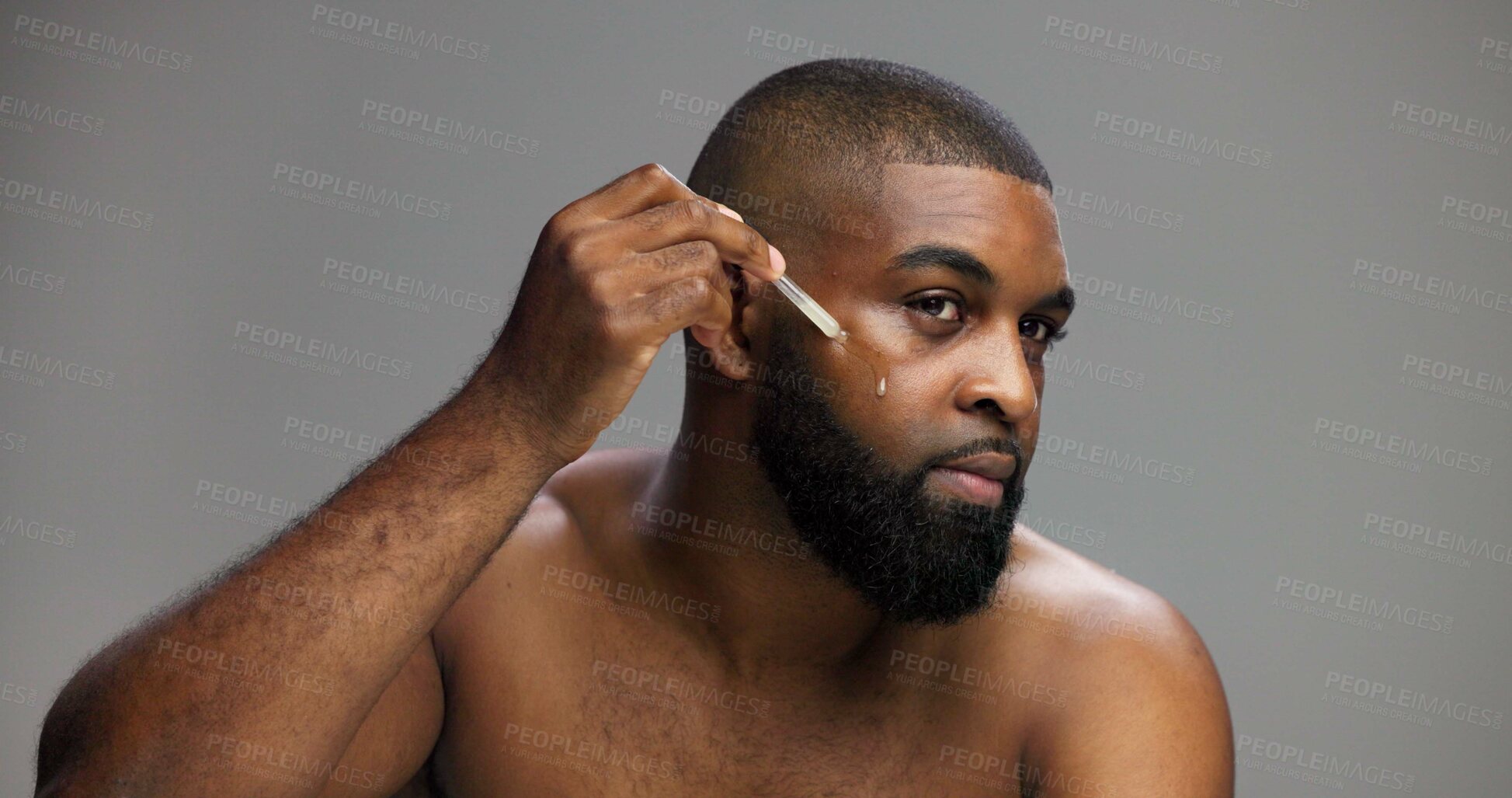 Buy stock photo Beauty, skincare and serum with black man in studio for facial, grooming and dermatology. Cosmetics, glow and self care with person and oil dropper on gray background for hydration, hygiene or shine
