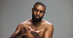 Facial, skincare and serum with black man in studio for beauty, grooming and dermatology. Cosmetics, glow and self care with person and dropper on gray background for hydration, hygiene and shine