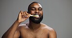 Toothbrush, happy and black man in studio for hygiene, fresh breath and mockup in morning. Portrait, wellness and person brushing teeth for dental care, cleaning or grooming on grey background space
