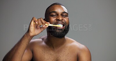 Buy stock photo Toothbrush, happy and black man in studio for hygiene, fresh breath and mockup in morning. Portrait, wellness and person brushing teeth for dental care, cleaning or grooming on grey background space

