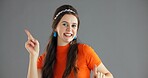 Happy woman, point and info in studio for advertising dance, announcement or news about us on gray background. Mockup space, portrait or coming soon with energy movement, sign or direction for launch