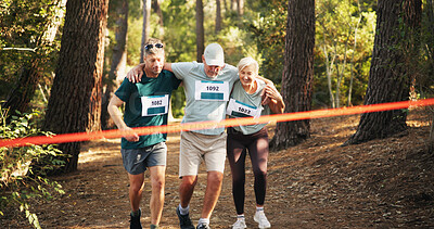 Buy stock photo Marathon, people running and help to finish line for exercise aid, fitness and challenge together in forest. Mature team, runner and support for race with leg injury, sprain or tired at sports event