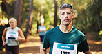 Marathon, portrait and running with man in forest for challenge, performance or race. Cardio, competition and fitness with mature runner at rally event in nature or woods for course, heat or trial