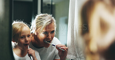 Buy stock photo Mom, child and brushing teeth with mirror in bathroom for morning routine or cleaning mouth at home. Mother, daughter or kid with toothbrush for fresh breath, dental hygiene or oral care at house