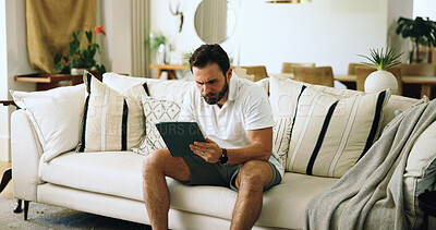 Buy stock photo Home, typing and man on sofa, tablet and internet with online reading, serious and investment. Apartment, tech and person on couch, connection and tax report with digital app for savings and trading