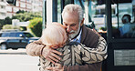 Senior couple, hug and travel in city for greeting, reunion and journey for visit at bus stop. Elderly people, passenger and embrace for commute of public transport, parting gesture and farewell trip