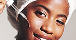 Portrait, beauty and woman with serum, skincare and smile for smooth skin with routine and moisturizing. Gray background, hydration and black person with oil for treatment, studio and grooming