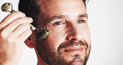 Buy stock photo Studio, beauty and man with roller, skincare and facial treatment to improve blood circulation and glow. White background, routine and person with jade tool for smooth skin, shine and self care