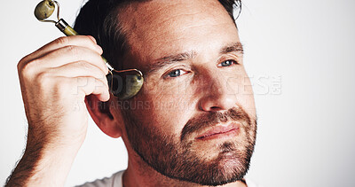 Buy stock photo Studio, glow and man with roller, skincare and facial treatment to improve blood circulation and beauty. White background, routine and person with jade tool for smooth skin, shine and self care