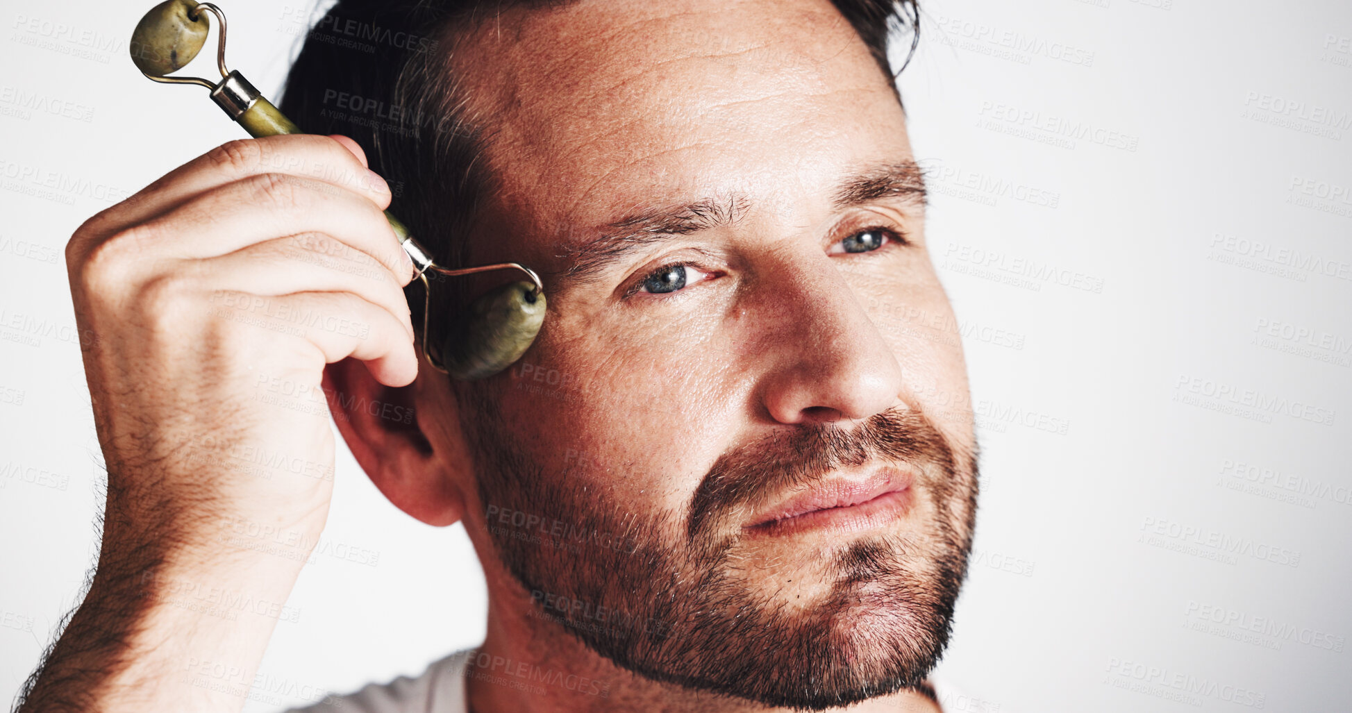 Buy stock photo Studio, glow and man with roller, skincare and facial treatment to improve blood circulation and beauty. White background, routine and person with jade tool for smooth skin, shine and self care