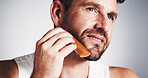 Thinking, comb and man with beard in studio for wellness, grooming and haircare on white background. Happy, space and person with tools for facial hair styling, growth and shave for morning routine