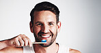 Portrait, man and smile for brushing teeth in studio for dental hygiene, fresh breath and oral care. Male person, toothbrush and treatment with plaque removal, whitening benefits and white background