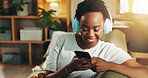 Headphones, black woman and happy with phone on sofa for streaming subscription, music playlist and search song. Relax, person and smartphone for social media video and listening to podcast in home